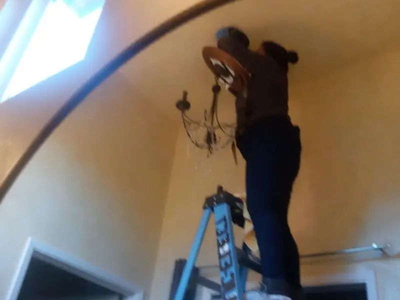 Electrician installing a chandelier in a Sandy residence